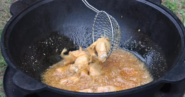 Fried Chicken Wings in a Frying Cauldron on Wood