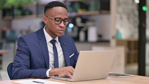 Attractive African Businessman with Laptop Looking at Camera in Office