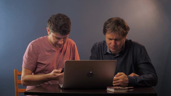 Man with Phone Shows How To Input Data To Senior Father