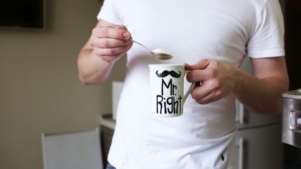 Man Stirs Sugar In a Cup Of Coffee