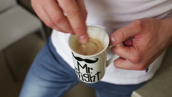 Man Stirs Sugar In a Cup Of Coffee