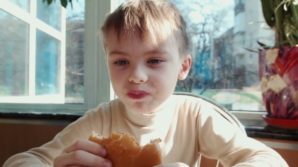 Boy Eating Hamburger In Fast Food Restaurant