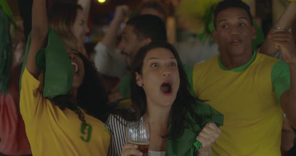 Brazilian football fans celebrating victory in sports bar, slow motion