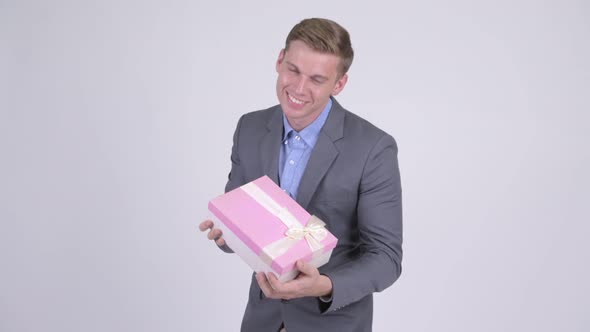 Happy Young Handsome Businessman Holding Gift Box and Giving Thumbs Up