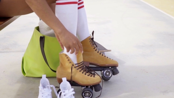 Young Woman Sits On Bench To Tie Her Skates