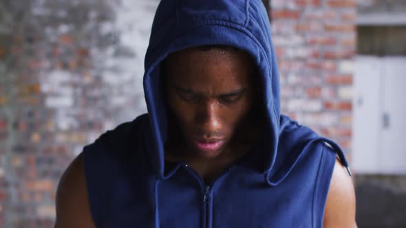 Portrait of african american man wearing hoodie sweating after exercise looking at camera in urban b