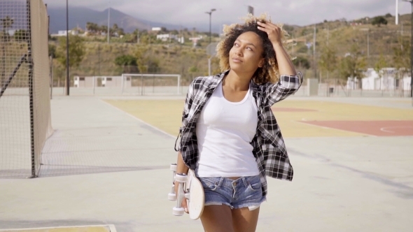 Young Woman With Skateboard Poses By Ball Court