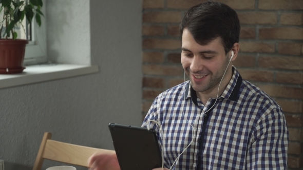 A Man Holding a Tablet In The Ears Headphones, Welcomed Companion Online.