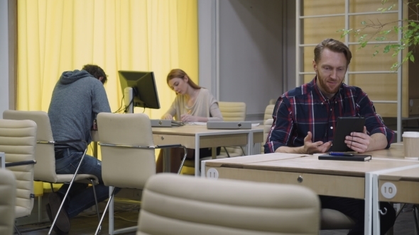 Open Space People Work, Man In Headphones Speaks With a Tablet.