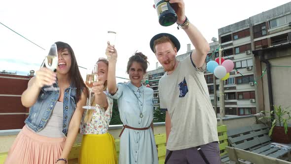 Four happy friends looking at camera and toasting with champagne