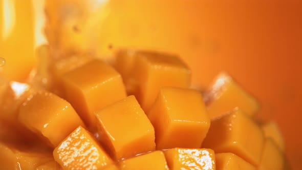 Slow Motion Shot of Mango Juice Splashing Through Mango Cube Slices