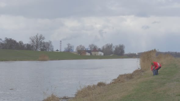 Man is Standing at River Bank Sits Takes a Laptop