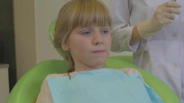 Girl Patient in a Chair Dentist Puts a Suction