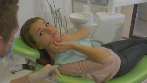 Woman Talking to Dentist Touches a Jaw Feels