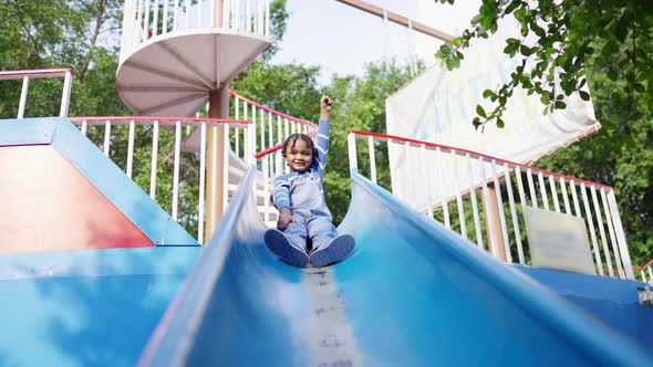 4K Little African boy sliding and playing at playground in the park