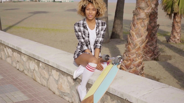 Cute Teenager Sitting On Ledge With Skateboard