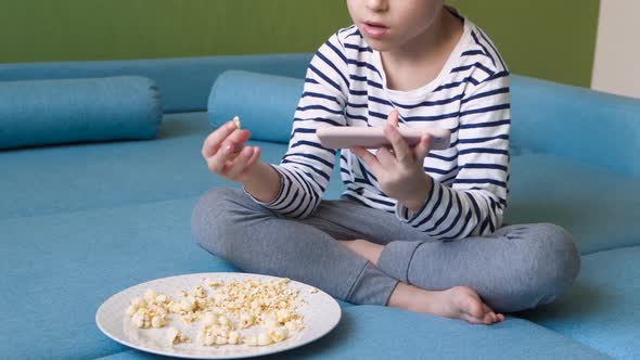 Kid Eat Popcorn and Spending Time Online Using your Smartphone