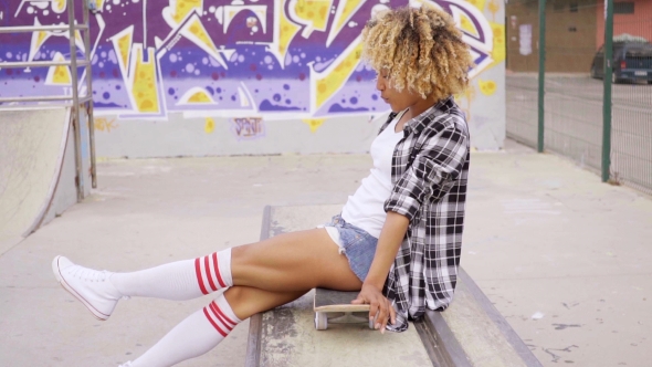 Trendy Young Woman Sitting On a Skateboard