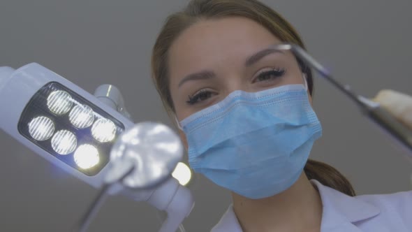 Young Dentist in Mask Approaches With a Tools