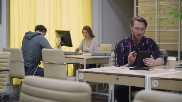A Bearded Man Talking On a Tablet In The Eco Office  alt