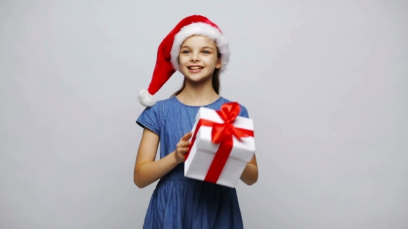 Happy Smiling Girl In Santa Hat Holding Gift Box