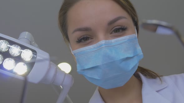 Dentist in Mask is Holding a Hook Mirror Smiling