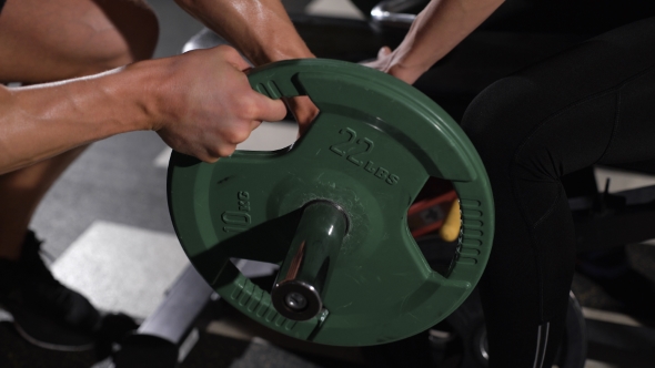 Bodybuilder Puts Weight On The Barbell.