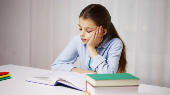 Bored School Girl Reading Book Or Textbook At Home