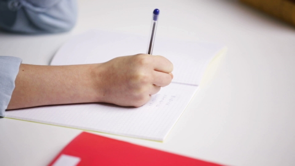 School Girl Hand Writing Math Task To Notepad