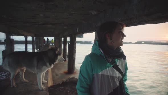 Young Beautiful Female Walking with Siberian Husky Dog on the Beach at Sunset Slow Motion