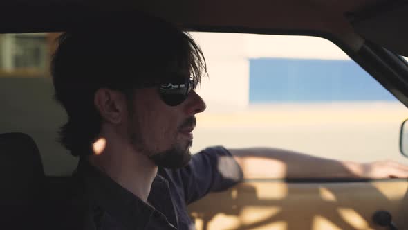 Portrait of Handsome Man in Old Classic Powerful Car on Street at Sunset or Sunrise