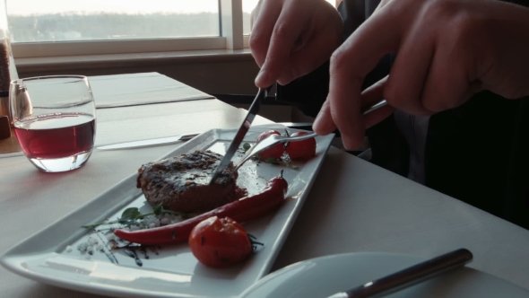 The Man With a Knife Cuts The Steak On a Plate