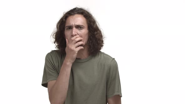 Video of Attractive Young Man with Wavy Hair Wearing Casual Tshirt Grimacing and Gasping Shocked