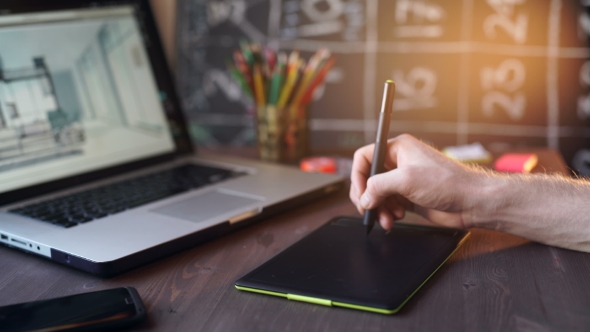 Creative Businessman Writing On Graphic Tablet While Using Laptop In Office