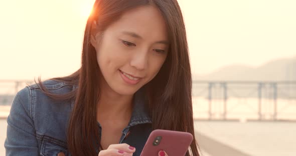 Woman look at smart phone in city under sun flare