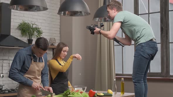 videographer filming kitchen scene. couple in love preparing healthy meal at home kitchen