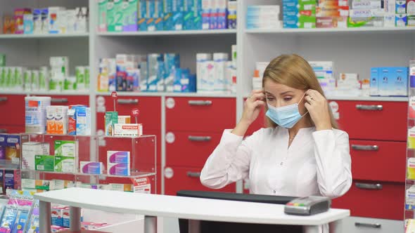 Caucasian Female Druggist in Medical Mask Dealing with a Male Customer.