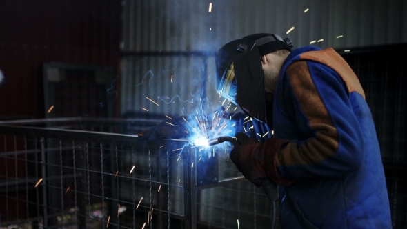 Welder Works In The Dark Of The Workshop