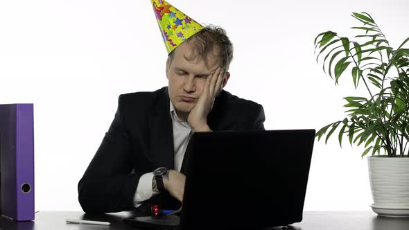 Drunk Sleepy Young Businessman with Hangover in Festive Cap Falling Asleep