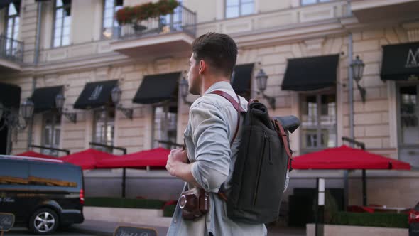 Attractive Young Handsome Man Tourist with Backpack Walking in City Center and Looking Around Slow
