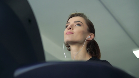 Girl With Headphones On a Treadmill