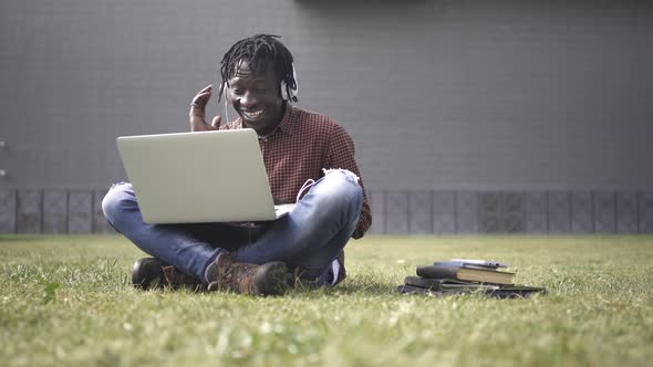 Black African American student in online video call using laptop at outdoors University campus