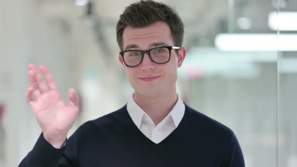 Cheerful Young Businessman Waving at the Camera 