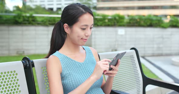 Woman Use of Mobile Phone and Sitting at Outdoor 