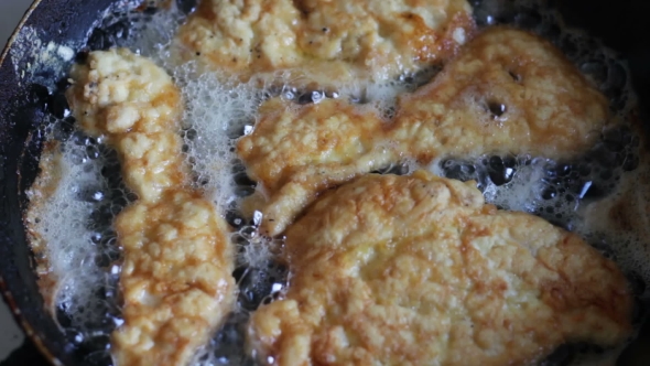 Woman Cook Roasts Meat Chops In a Skillet On The Home Kitchen alt