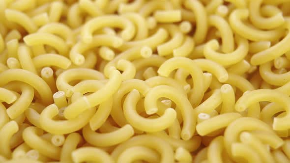 Dry yellow gobetti pasta. Carbohydrate wheat vegetarian food. Macro. Falling in slow motion