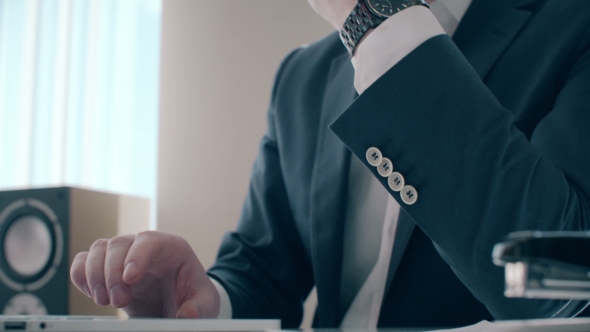 Businessman Working On Laptop Computer In The Office. He Checks Time And Go To Break