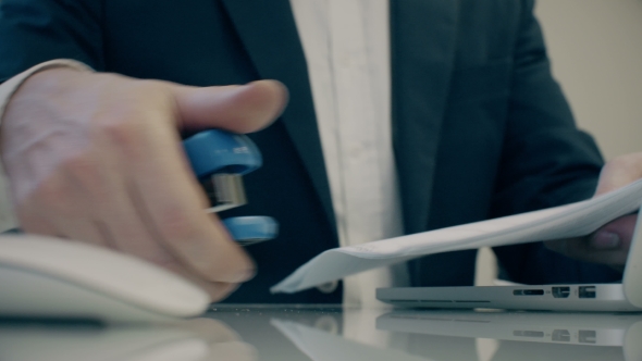 Businessman Uses Stapler And Notebook