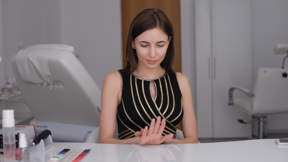 Beauty Parlour. Attractive Young Brunette Looks At Her New Manicure