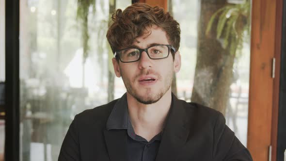 Young business man in suit wearing glasses talk on camera